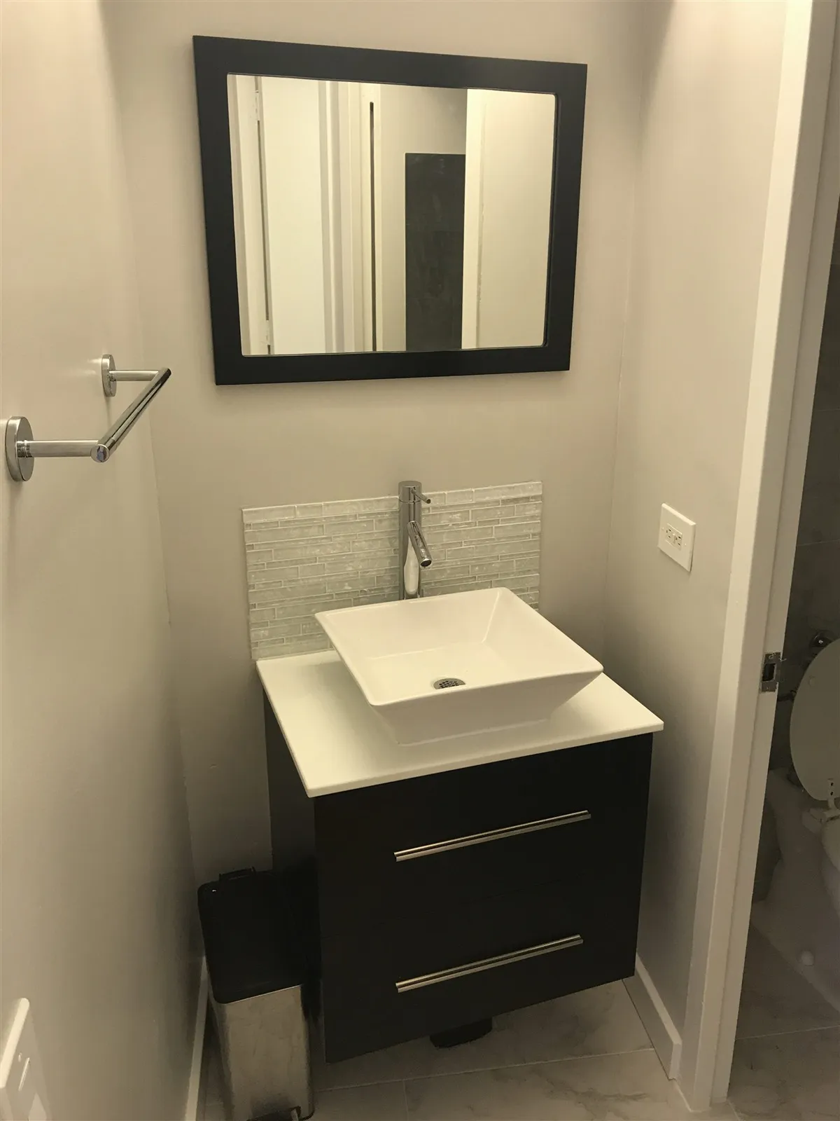 Small bathroom with black vanity and framed mirror