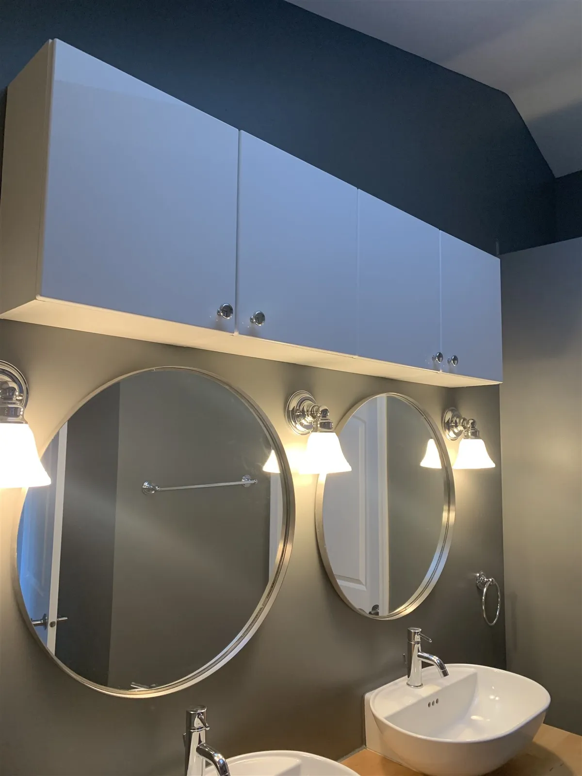 Bathroom with round mirrors, vessel sink and wall sconces