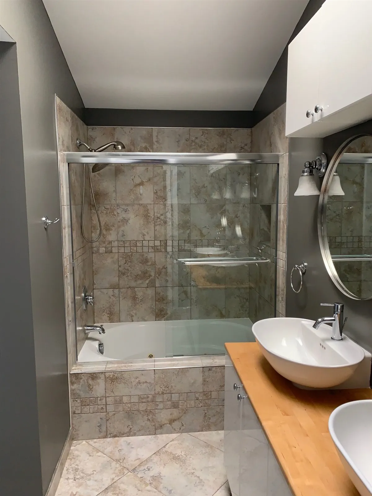 Remodeled bathroom with glass shower, stone tile and vessel sink