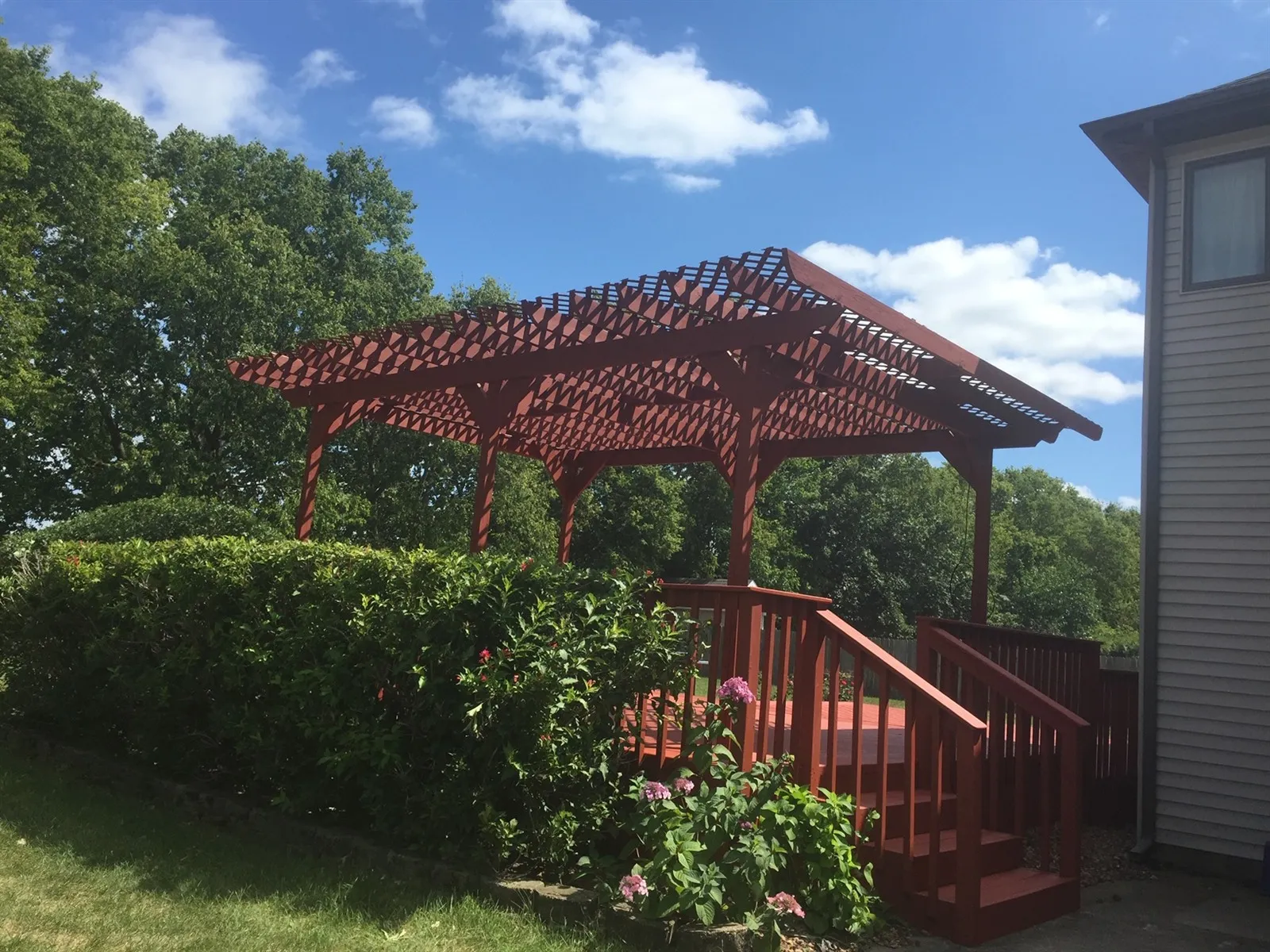 Wood deck with a pergola and stairs seen from the yard