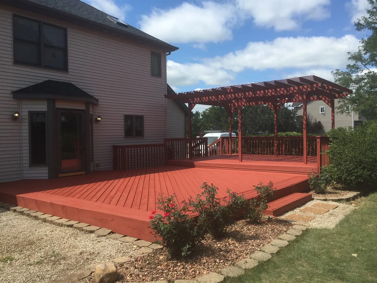 Large stained wood deck with a pergola behind a Chicago-area home