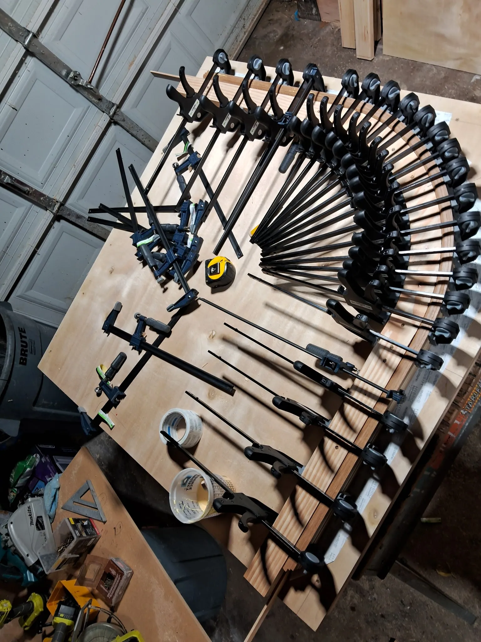 Dozens of clamps pressing glued oak strips into a curve on a plywood form