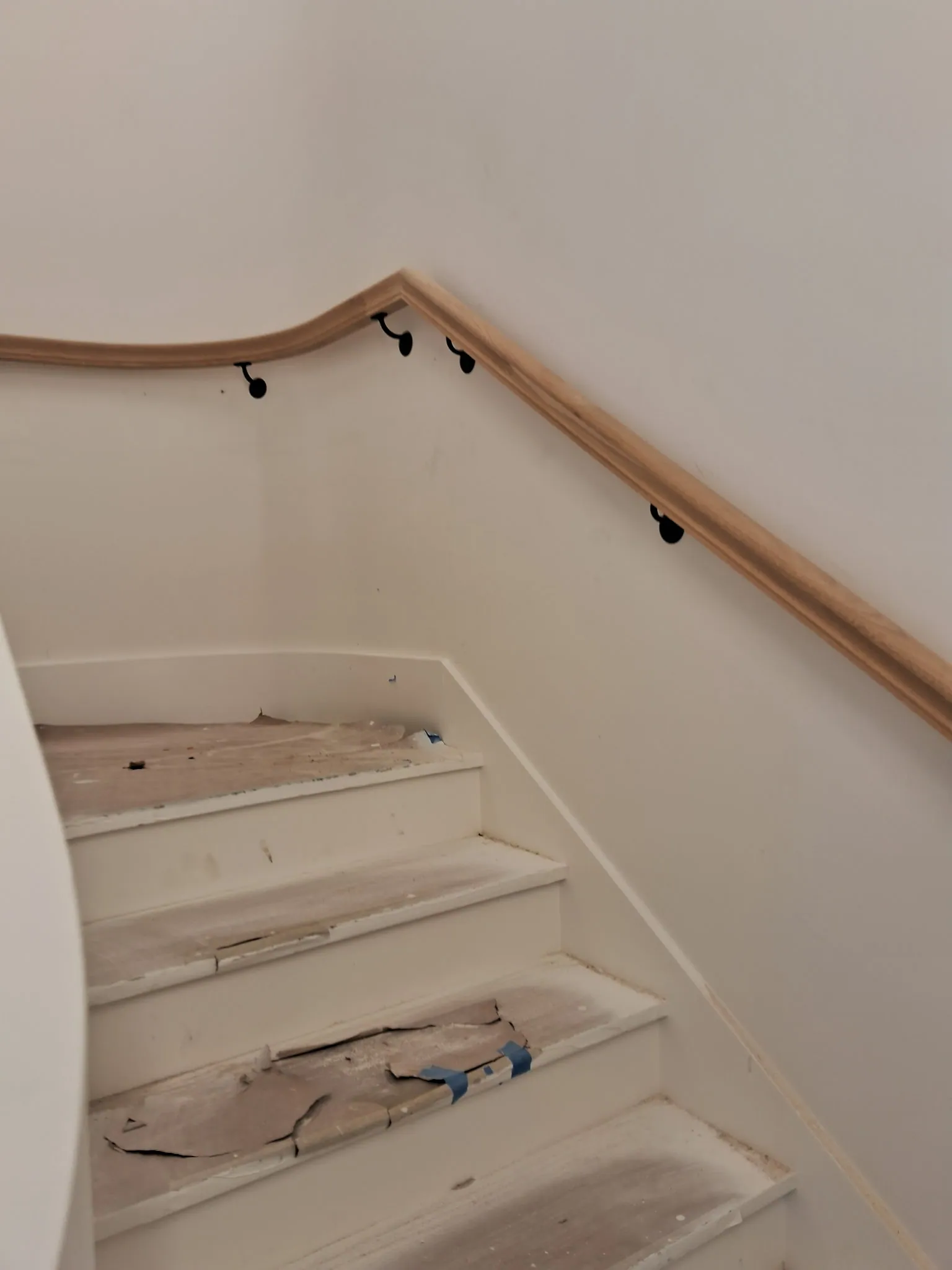 Oak handrail on black brackets curving along a stair wall