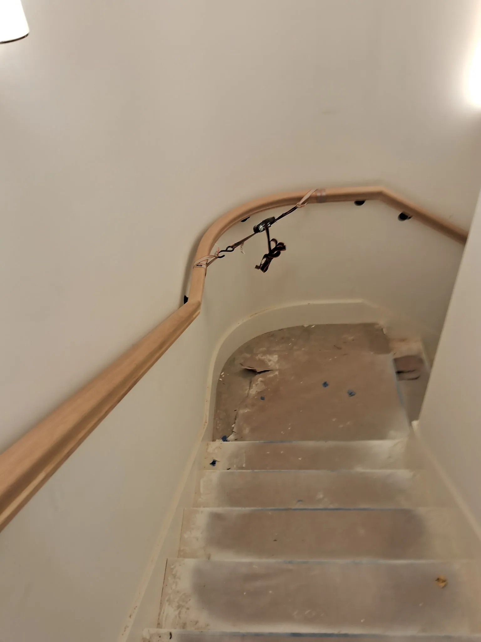 Bent oak handrail following a turn on a stair with black wall brackets