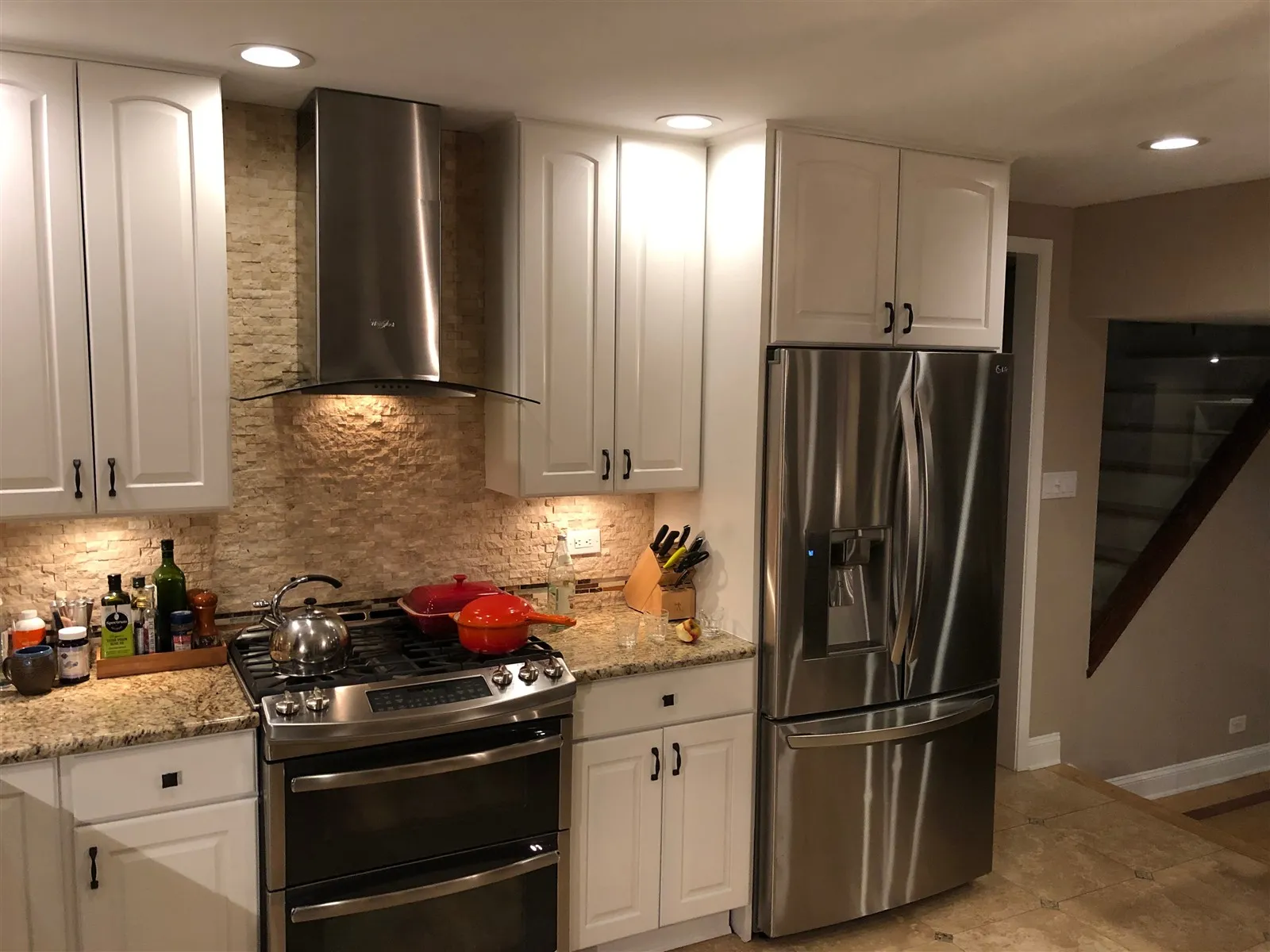 Remodeled kitchen with white cabinets and stainless appliances