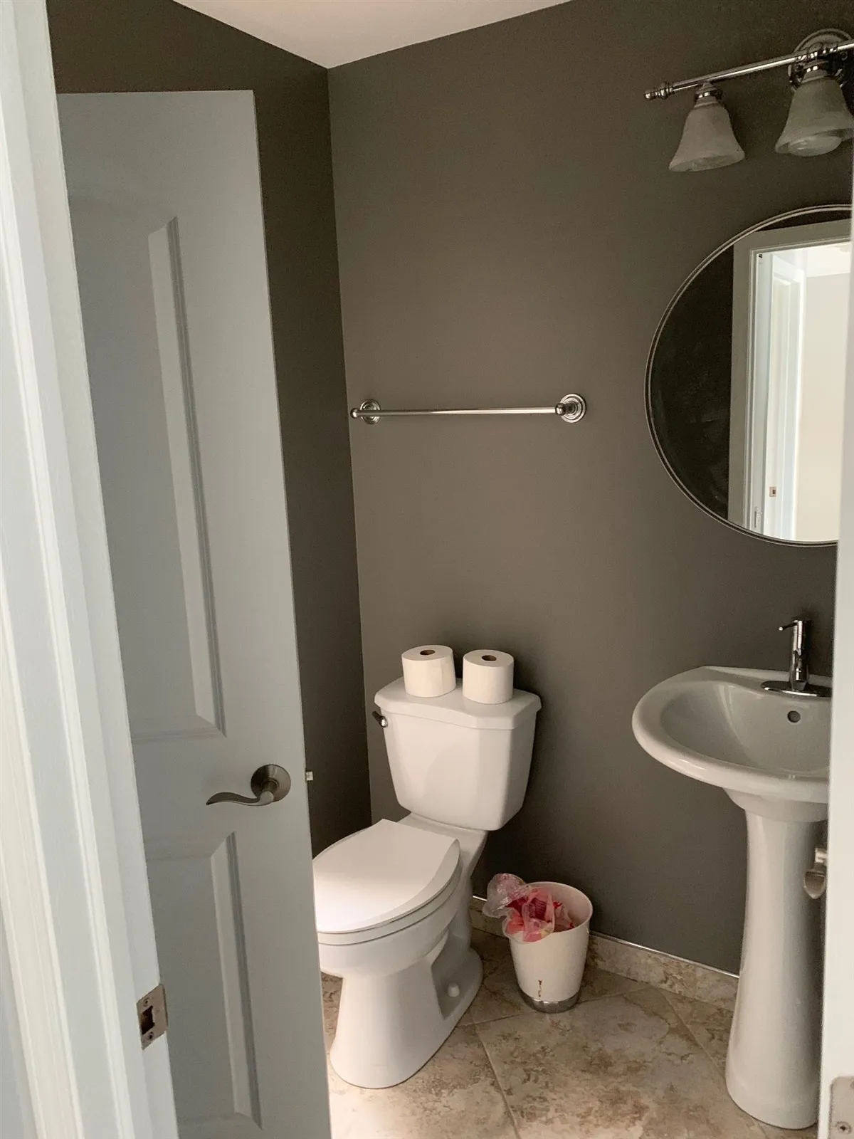 Powder room with pedestal sink and oval mirror